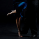 Dettaglio delle gambe di una coppia di tango argentino, lei in abito blu su fondo scuro