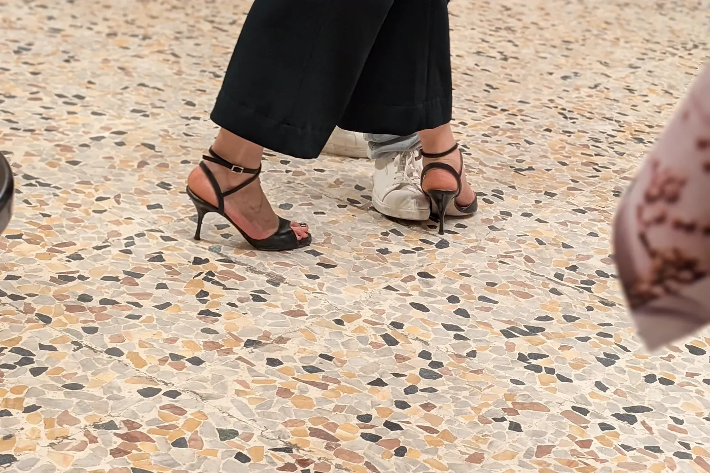 Scarpe da tango e scarpe da ginnastica sullo stesso pavimento durante una serata di tango argentino