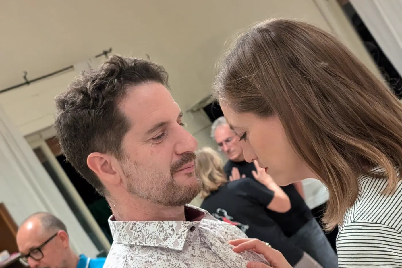 Due allievi provano l'abbraccio del tango argentino durante una lezione, con il resto della classe sullo sfondo